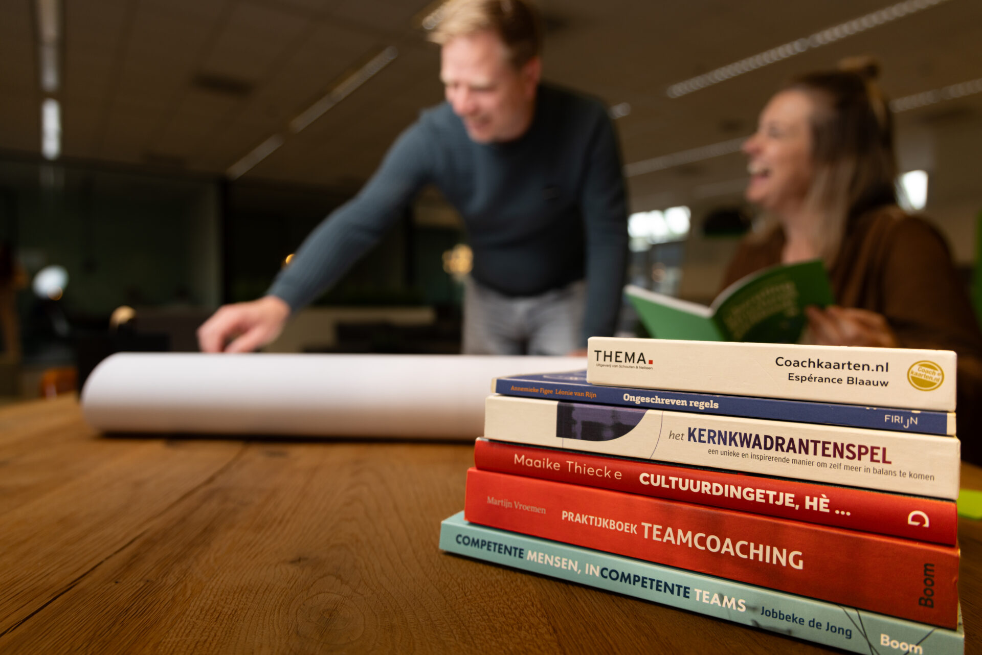 Paul en Marieke werken aan een flipover, boeken op de voorgrond.